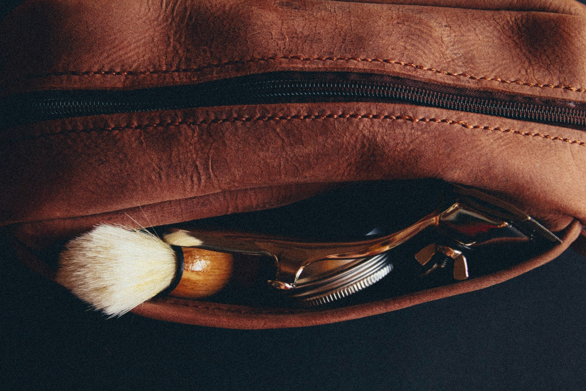 A leather dopp kit with a shaving brush